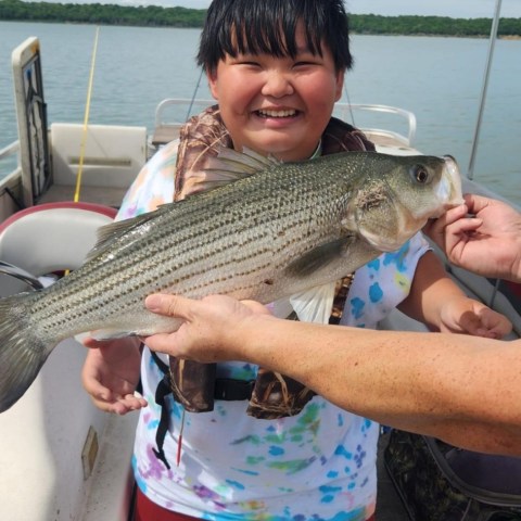 a person holding a fish on a boat in a body of water